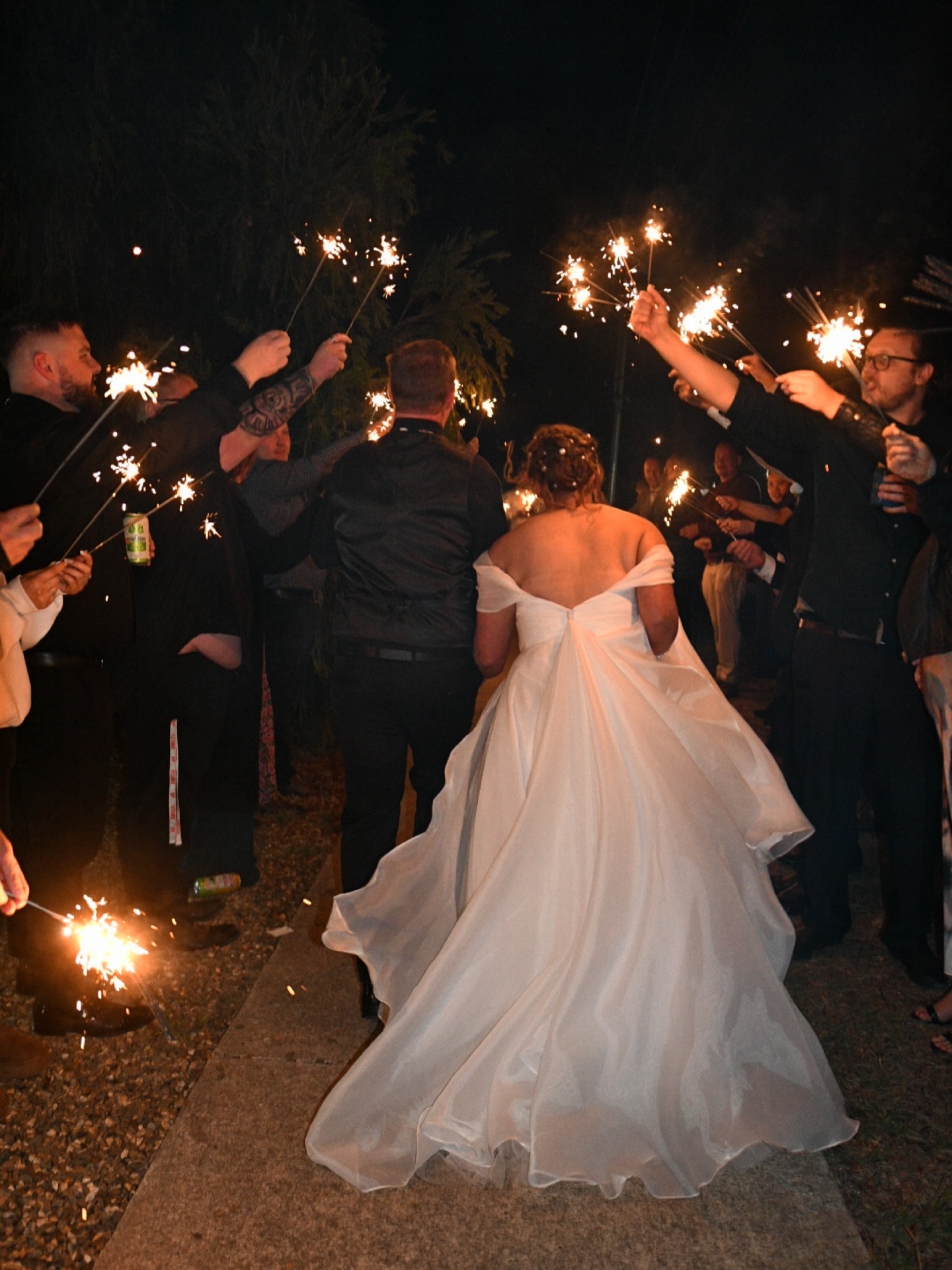 Bride and groom walking out through a tunnel of sparklers at night